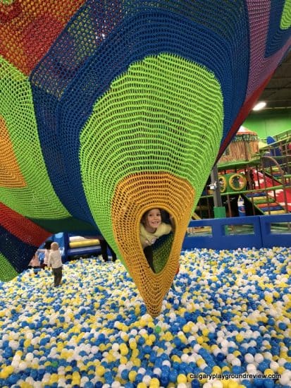 child peaking out of the net climber