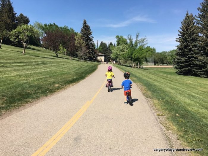 kids riding bikes towards the Confederation Park Natural Playground